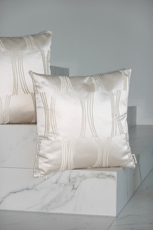 Two decorative pillows with a geometric pattern on a marble surface.