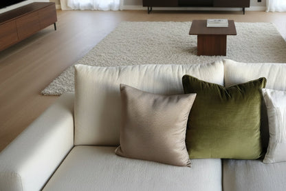 Three pillows on a sofa, including a green one, a beige one, and a white one.