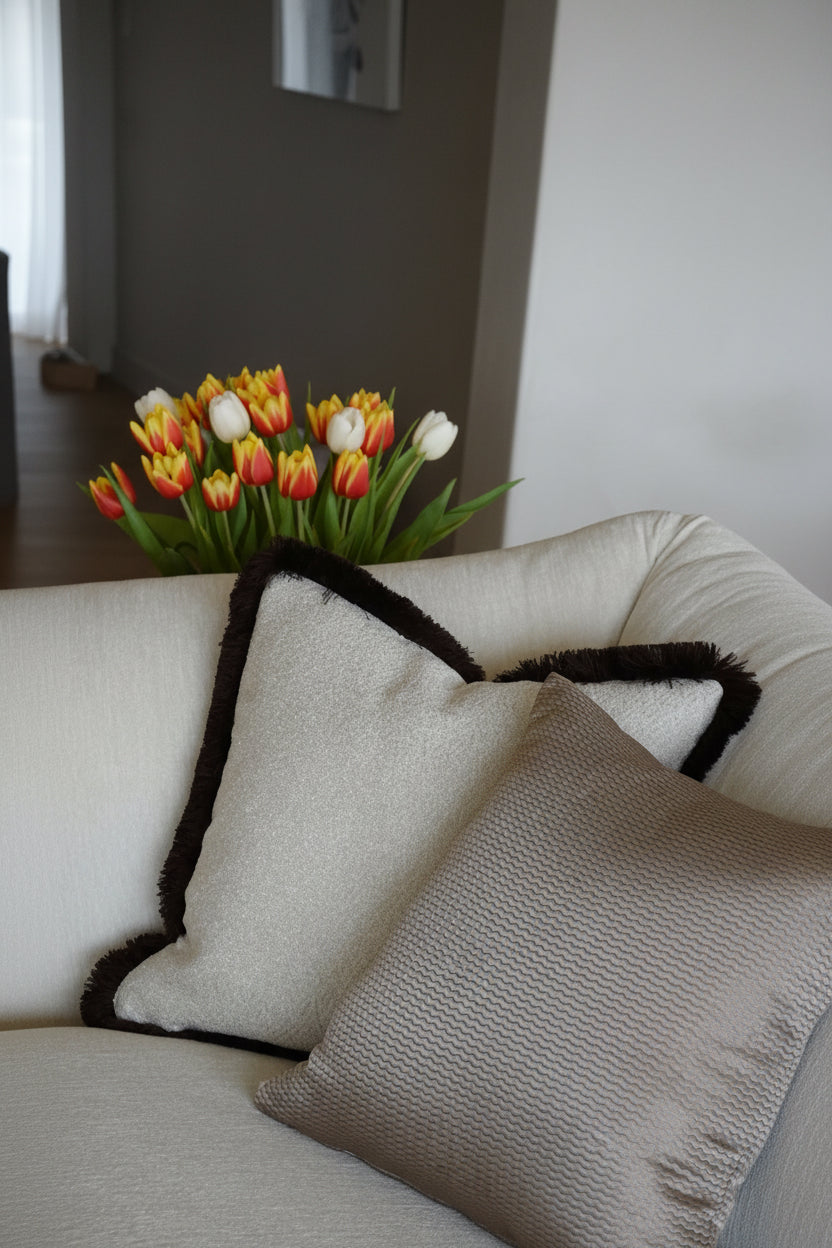 White sofa with decorative pillows and a vase of tulips on a table.