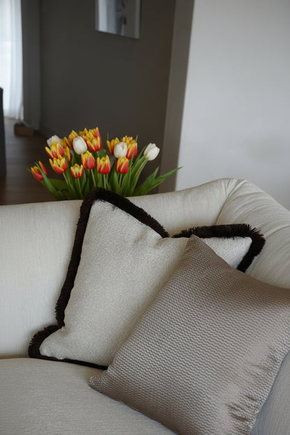 White sofa with decorative pillows and a vase of tulips on a table.