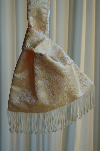 Decorative bag with gold patterns and fringes on a plain background